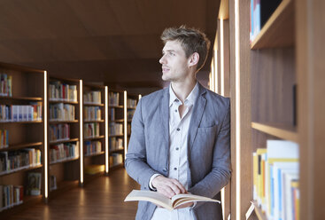 Young man with book in library - FMKF003045