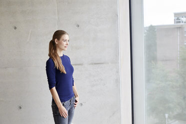 Young woman looking out of window - FMKF003050