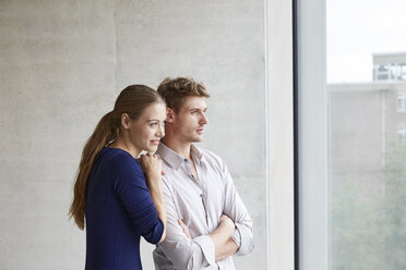 Young couple looking out of window - FMKF003052