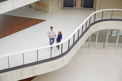 Junger Mann und Frau unterhalten sich in einem modernen Bürogebäude, lizenzfreies Stockfoto