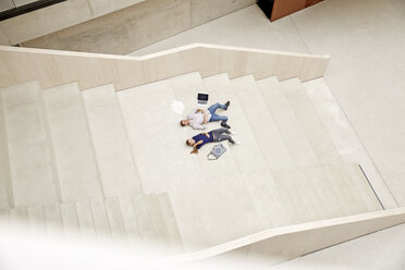 Junger Mann und Frau liegen auf einer Treppe in einem Gebäude - FMKF003055