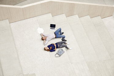 Junger Mann und Frau liegen auf einer Treppe in einem Gebäude - FMKF003056
