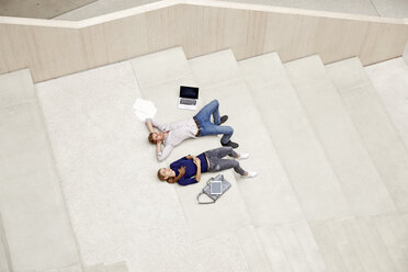 Young man and woman lying on staircase in a building - FMKF003056