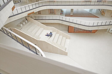 Junger Mann und Frau liegen auf einer Treppe in einem Gebäude - FMKF003057