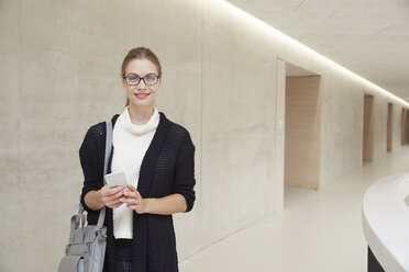 Smiling young woman on corridor of building - FMKF003063