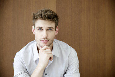 Portrait of confident young man in front of wooden wall - FMKF003073