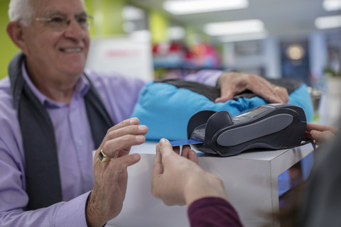 Senior man at counter paying with credit card stock photo