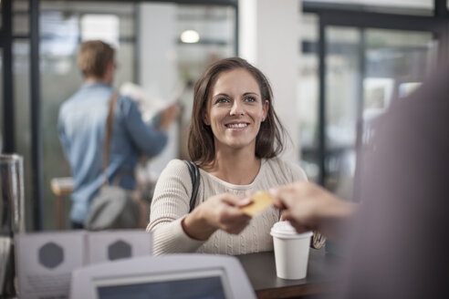 Der Kunde bezahlt den Kaffee zum Mitnehmen mit seiner Kreditkarte - ZEF009840