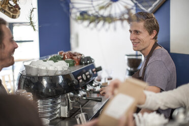 Young barista making coffee for customers - ZEF009842