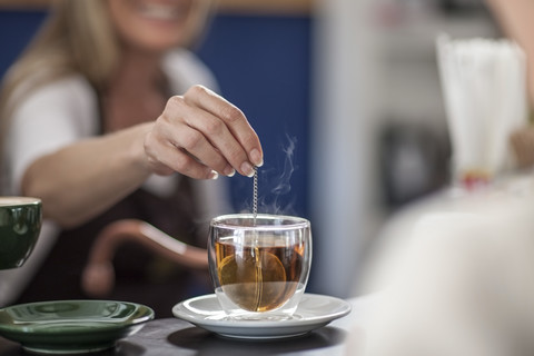 Frau in einem Café bereitet ein Glas Tee vor, lizenzfreies Stockfoto