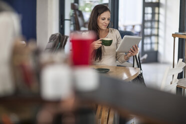 Woman using tablet in a cafe - ZEF009858