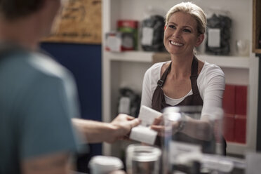 Frau in einem Café, die einem Kunden die Quittung übergibt - ZEF009860