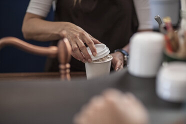 Barista schließt den Deckel eines Einweg-Kaffeebechers - ZEF009868