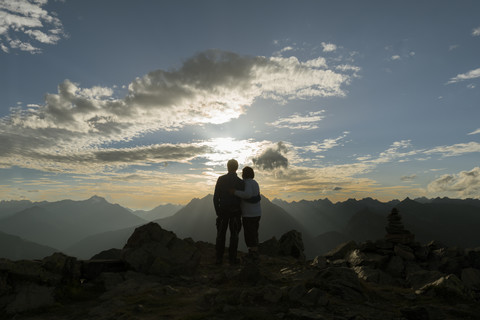 Glückliches Paar bei Sonnenuntergang in den Bergen, lizenzfreies Stockfoto