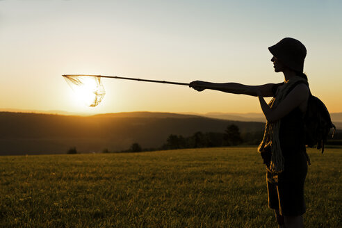 Female hiker catching sun with dip net at dawn - MIDF000791