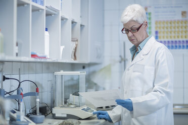 Senior woman in lab looking at paper - ZEF009940