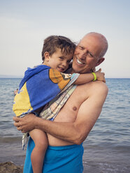 Happy grandfather standing at seashore holding grandson on his arms - XCF000104