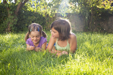 Two girls lying side by side on a meadow - LVF005226