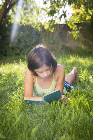 Mädchen liest Buch auf einer Wiese, lizenzfreies Stockfoto