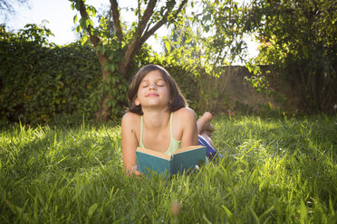 Fröhliches Mädchen auf der Wiese liegend mit einem Buch - LVF005231