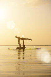 Thailand, Paar beim Yoga auf dem Paddelbrett bei Sonnenuntergang - SBOF000171