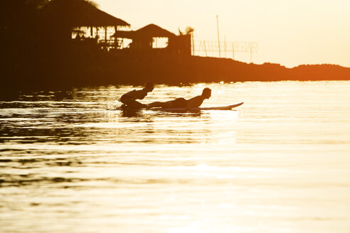 Thailand, Paar macht Yoga auf Paddleboard bei Sonnenuntergang, Kobra-Pose - SBOF000172