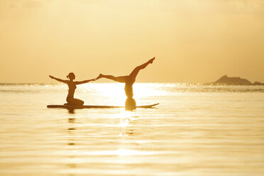 Thailand, Paar beim Yoga auf dem Paddelbrett bei Sonnenuntergang - SBOF000174