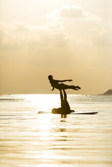 Thailand, Paar beim Yoga auf dem Paddelbrett bei Sonnenuntergang - SBOF000175