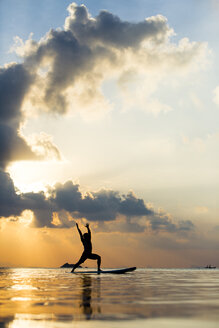 Thailand, Mann beim Yoga auf dem Paddelbrett bei Sonnenuntergang, Brückenstellung, Kriegerpose - SBOF000179