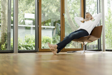 Man relaxing on chair in his living room - SBOF000190