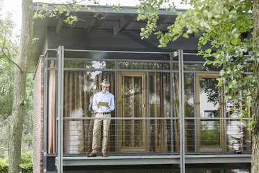 Man standing on balcony of his house using tablet - SBOF000191