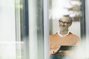 Mann mit Tablet, der durch ein Fenster schaut - SBOF000214