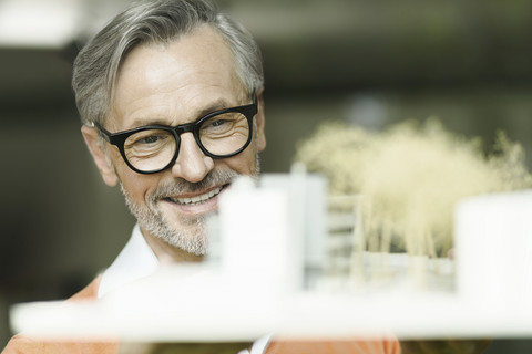 Portrait of smiling man looking at architectural model stock photo