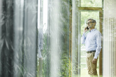 Man on the phone in his house looking through window - SBOF000234