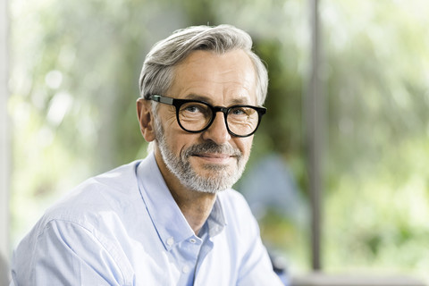 Portrait of smiling man with grey hair and beard wearing spectacles stock photo