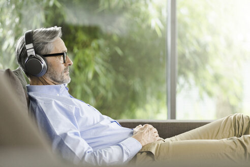Mann entspannt sich auf der Couch und hört Musik mit Kopfhörern - SBOF000246