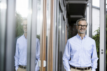 Portrait of smiling man reflecting at facade of his house - SBOF000251