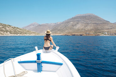 Greece, back view of woman sitting on bow of a boat looking at Amorgos Island - GEMF000992