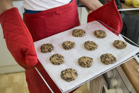 Frau zeigt ein Tablett mit frisch gebackenen Keksen, lizenzfreies Stockfoto