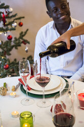 Frau serviert Wein an Mann beim Weihnachtsessen - ABZF001052