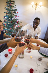 Freunde stoßen bei einem Weihnachtsessen mit Wein an - ABZF001062