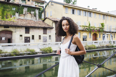 Italien, Mailand, Porträt einer jungen Frau mit Rucksack und weißem Sommerkleid - MRAF000118