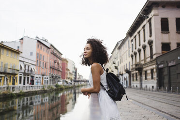 Italy, Milan, young woman with backpack leaning on railing looking at distance - MRAF000119