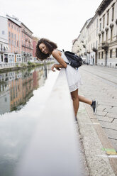 Italien, Mailand, glückliche junge Frau mit Rucksack am Geländer lehnend - MRAF000121