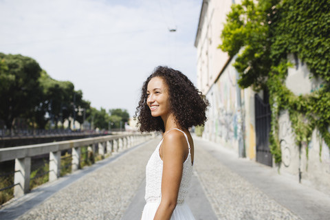 Porträt einer lächelnden jungen Frau mit lockigem braunem Haar, lizenzfreies Stockfoto