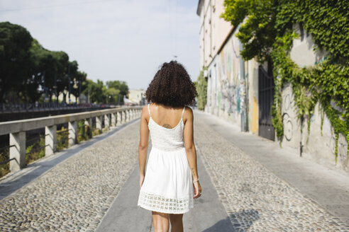 Back view of walking young woman wearing white summer dress - MRAF000130