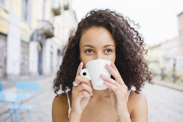 Young woman drinking coffee at sidewalk cafe - MRAF000142