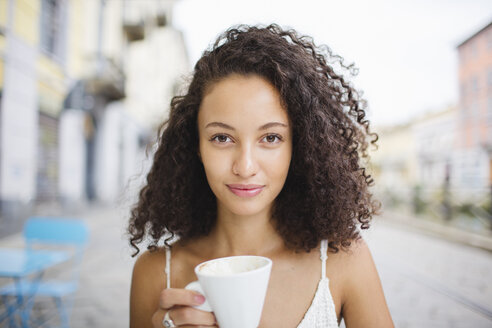 Porträt einer jungen Frau, die in einem Straßencafé Kaffee trinkt - MRAF000143