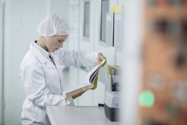 Labortechniker in steriler Schutzkleidung bei der Durchsicht von Akten - ZEF010024