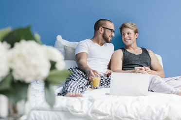 Schwules Paar im Bett liegend, mit Laptop - MADF001148